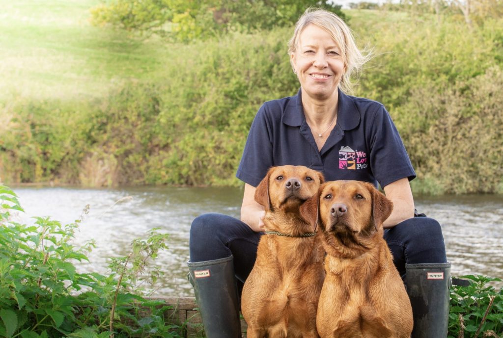 Jane from We Lovev Pets Guildford sitting with two dogs in between her legs