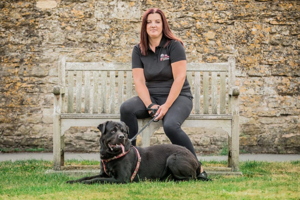 Jo from We Love Pets Trowbridge sitting on a bench with a dog laying in front of her