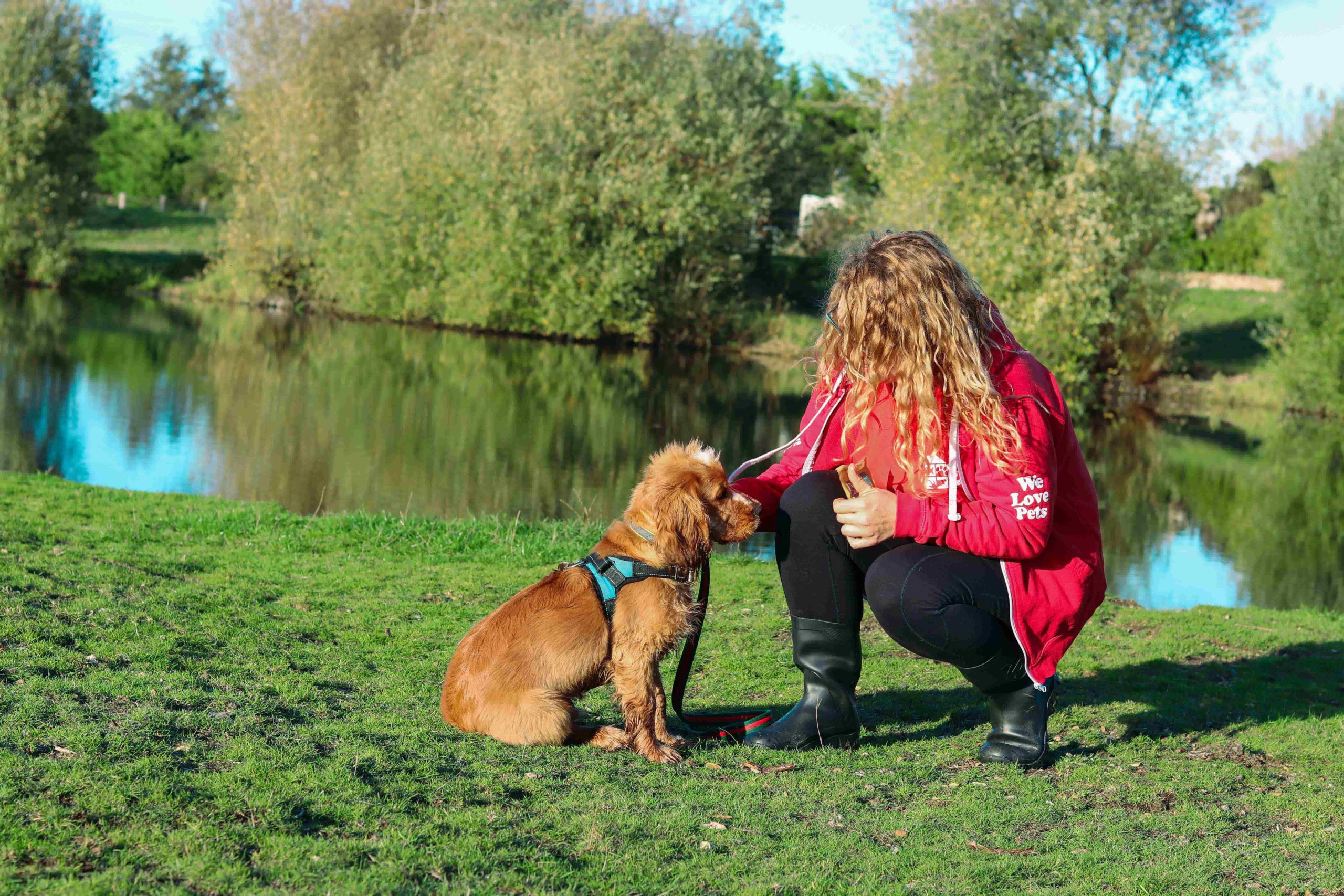 Leanne from We Love Pets Waveney crouching down next to sitting dog