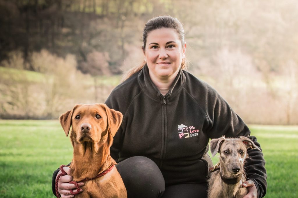 Robyn from We Love Pets Pendle kneeling with two dogs