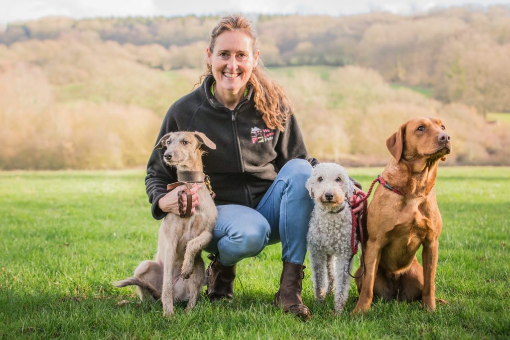 Sarah from We Love Pets Blackwood kneeling with three dogs