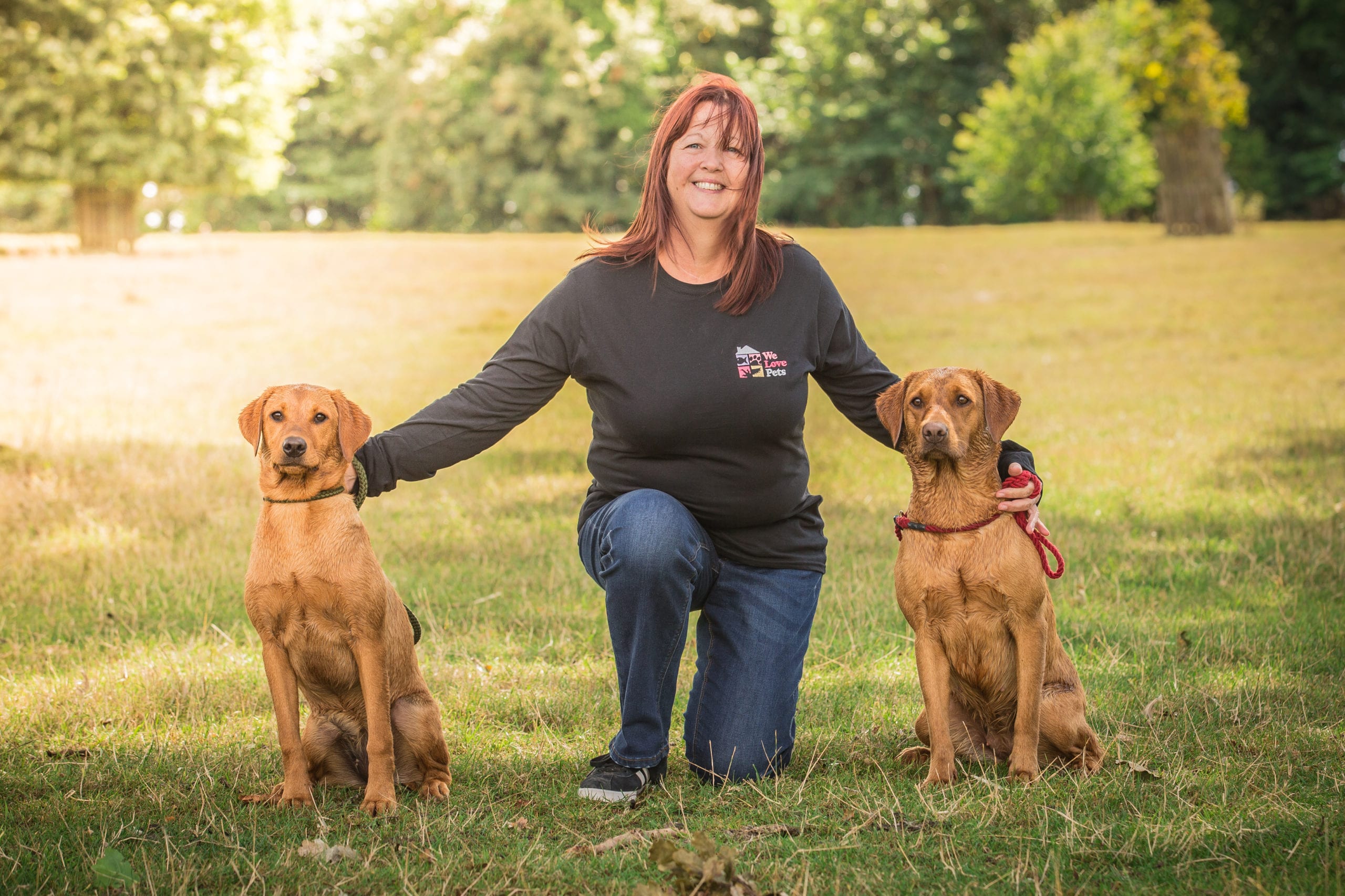 Shirley from We Love Pets Brentwood kneeling holding two dogs