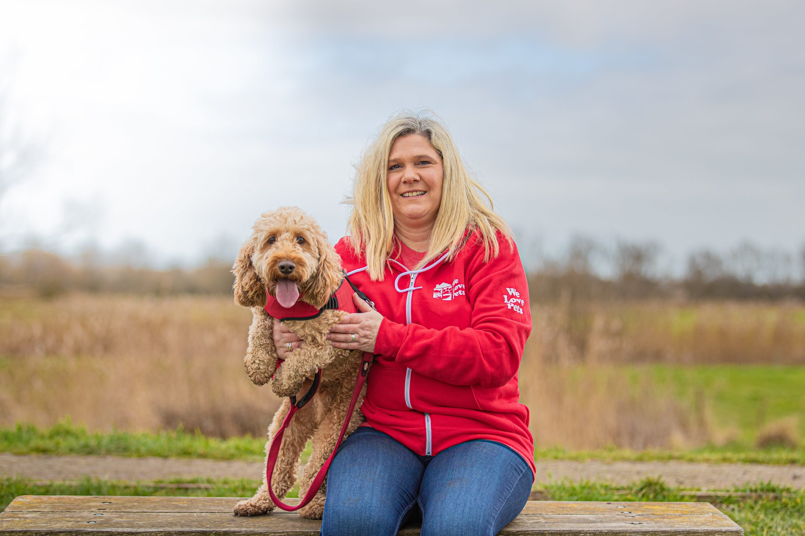 Charlotte from We Love Pets Stevenage sitting on a bench holding a dog