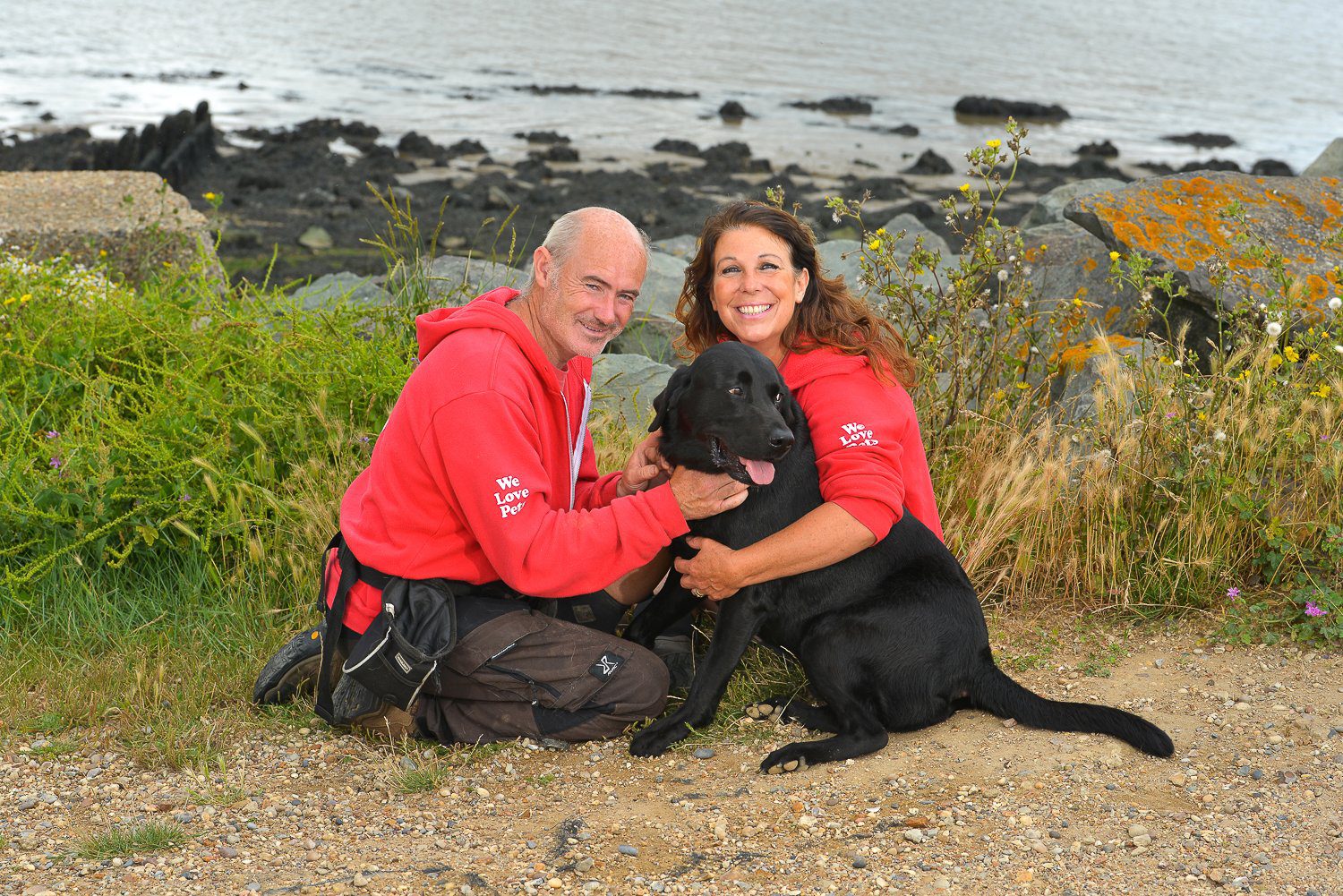 Man and woman from We Love Pets Colchester hugging a dog