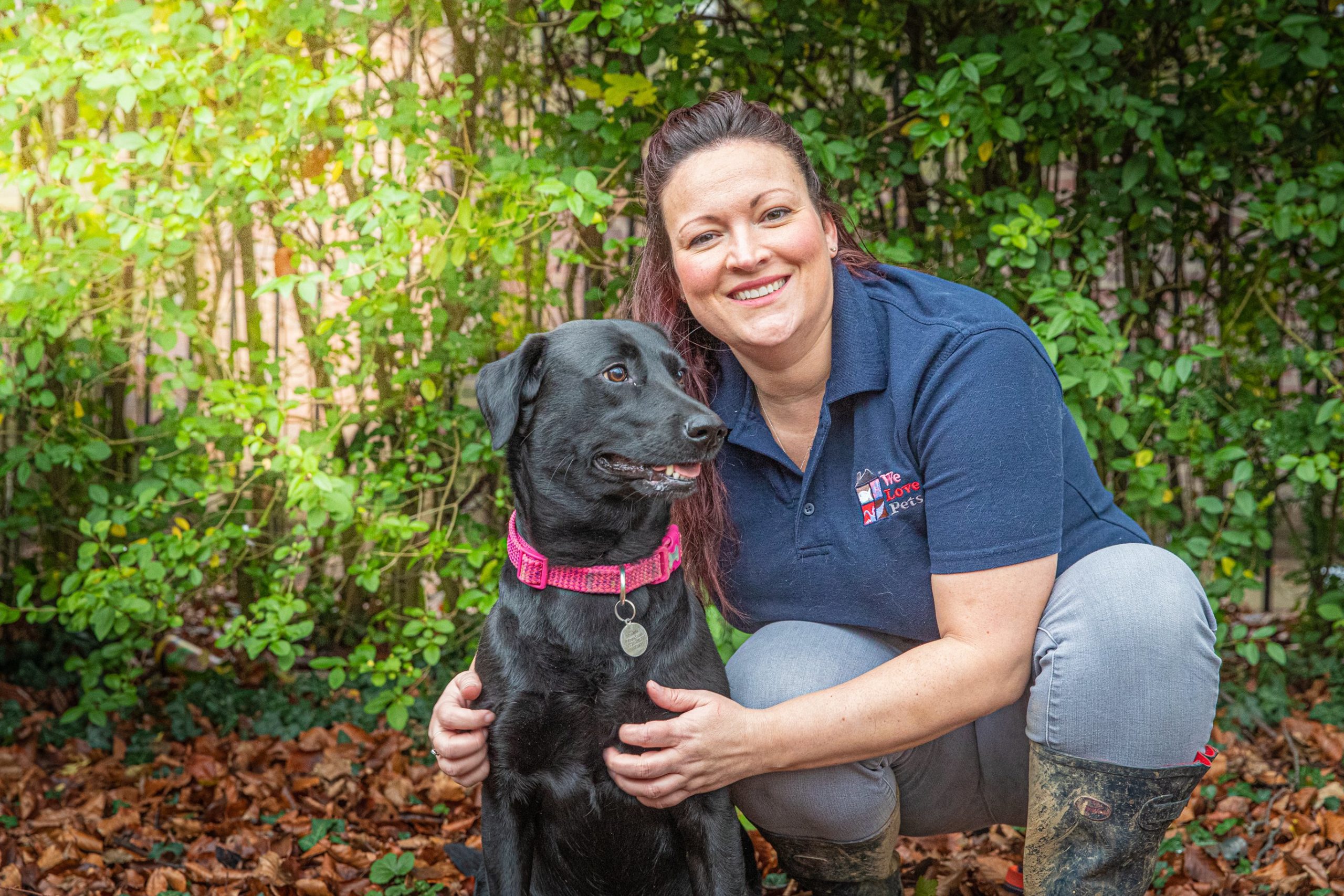 Kelly from We Love Pets Dunstable crouched down next to a dog