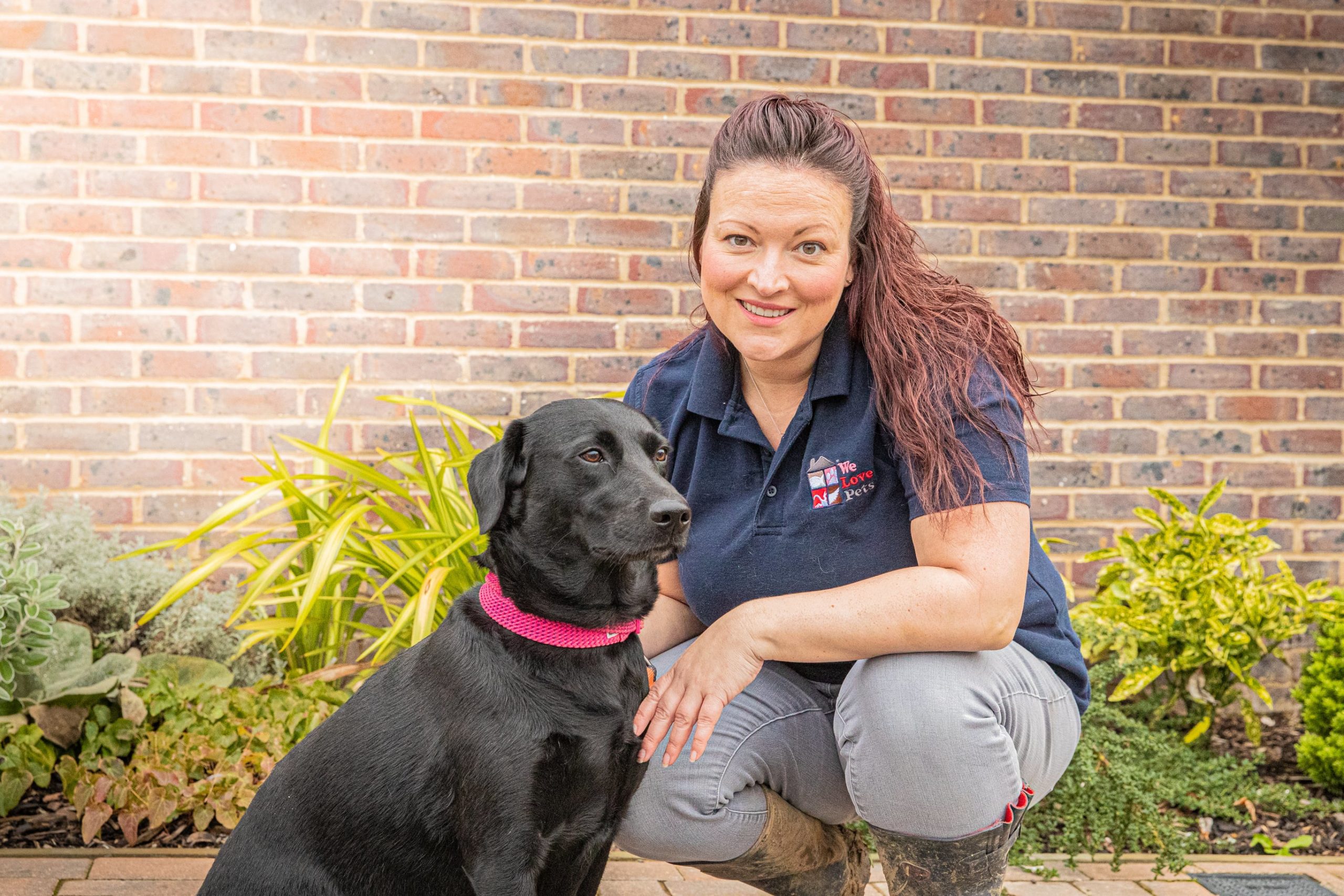 Kelly from We Love Pets crouched down next to a dog