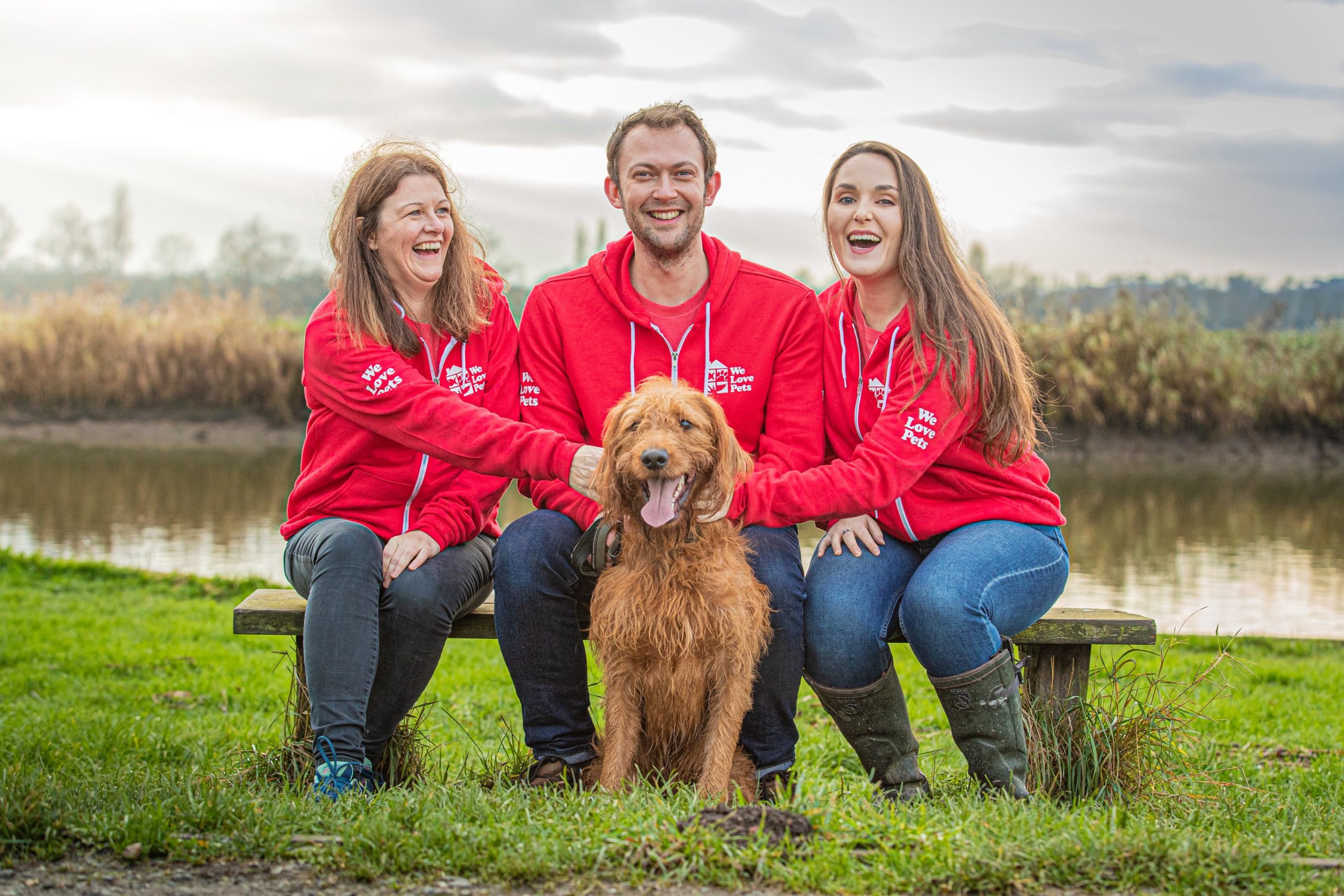 Three people sitting petting a dog