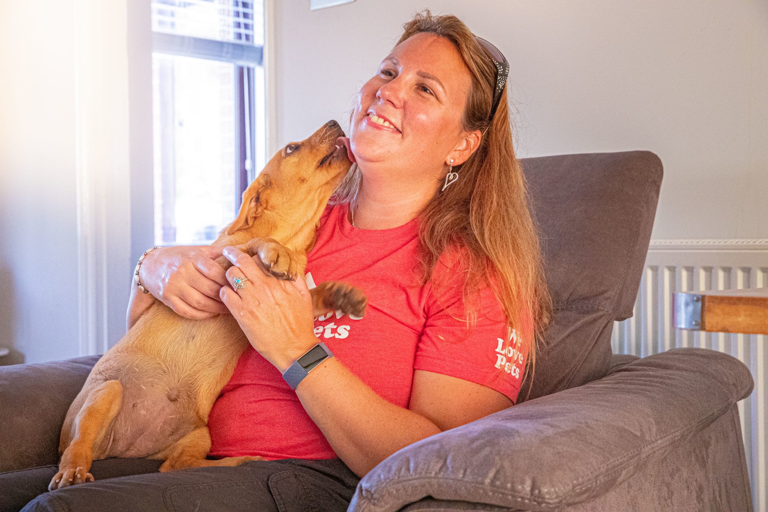 Rebecca from We Love Pets Derby holding puppy licking her face