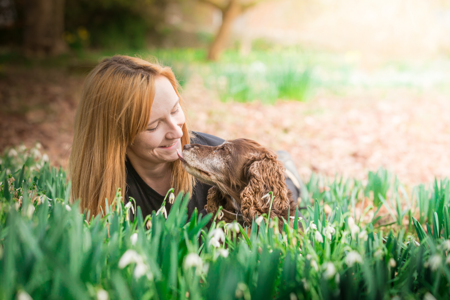 Woman laying with dog in grass