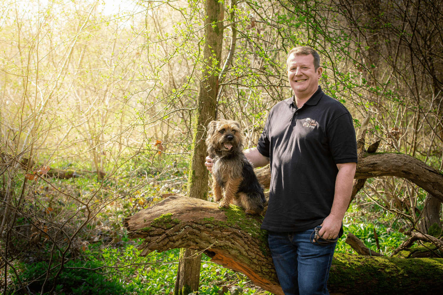 Man standing next to sitting dog on log