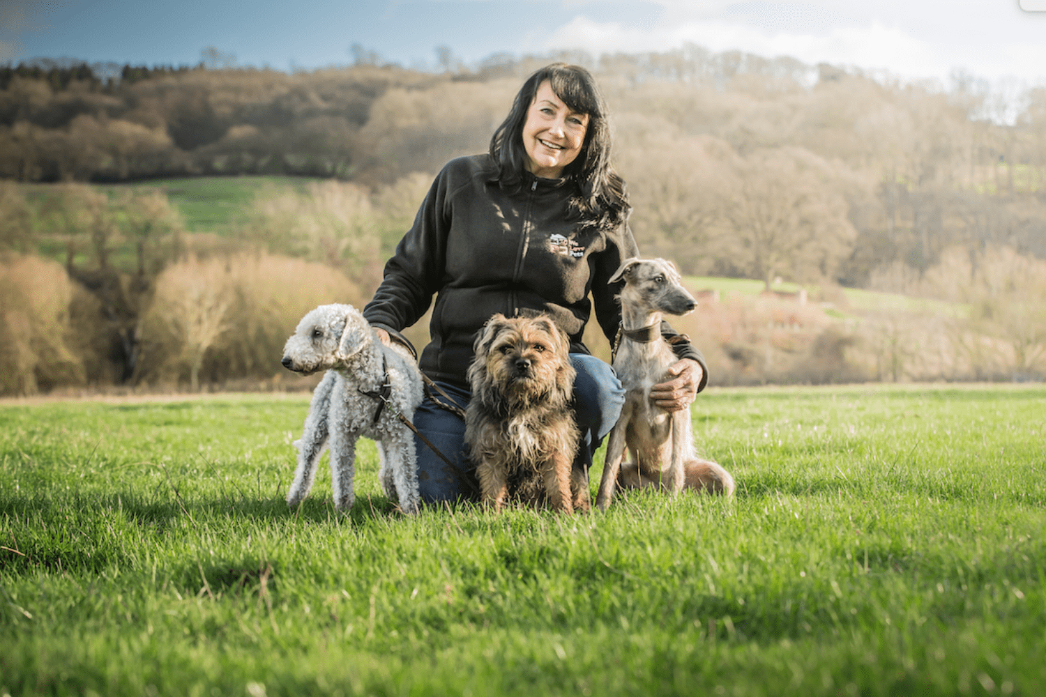 Woman crouched down holding three dogs