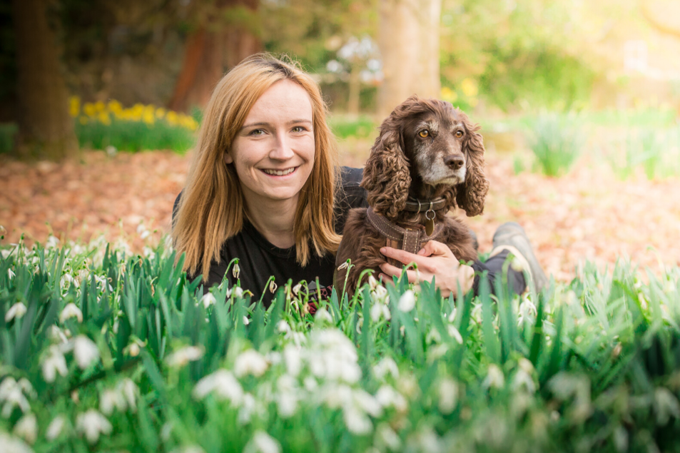 Woman from We Love Pets Bracknell laying with dog in grass