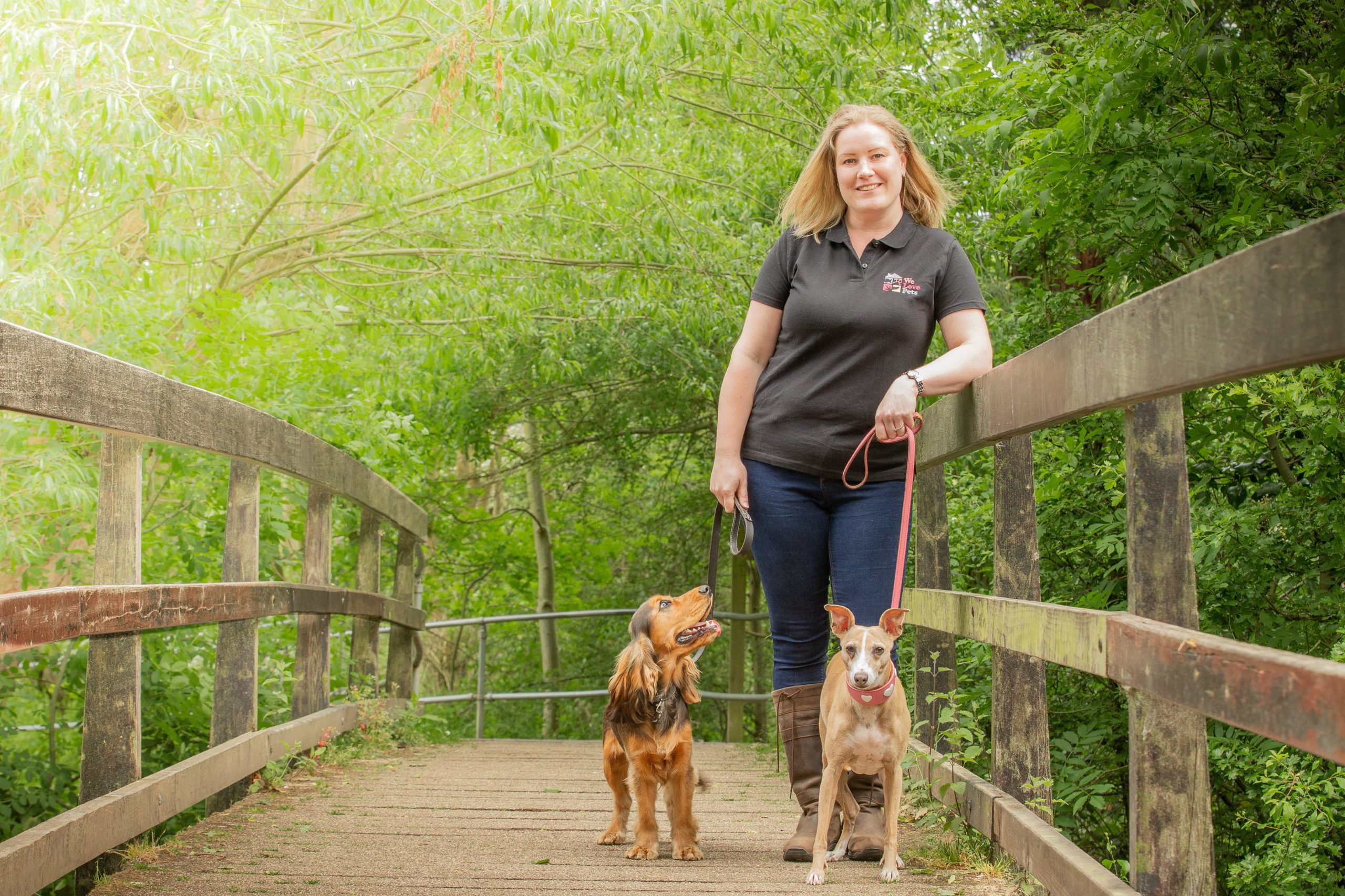 Claire from We Love Pets Knowle standing walking two dogs
