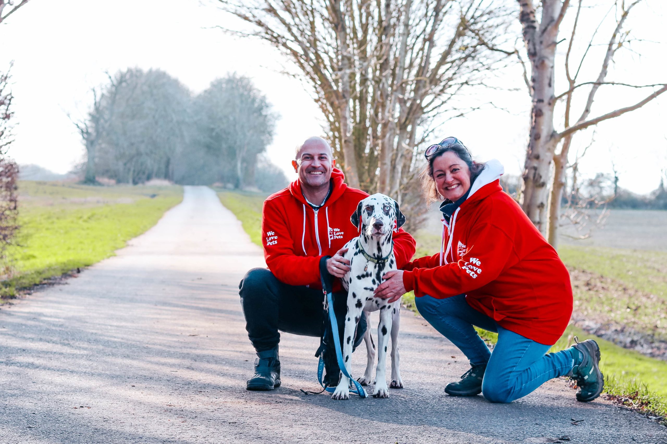 Tash and Andy from We Love Pets Bury St Edmunds crouching with a dalmatian