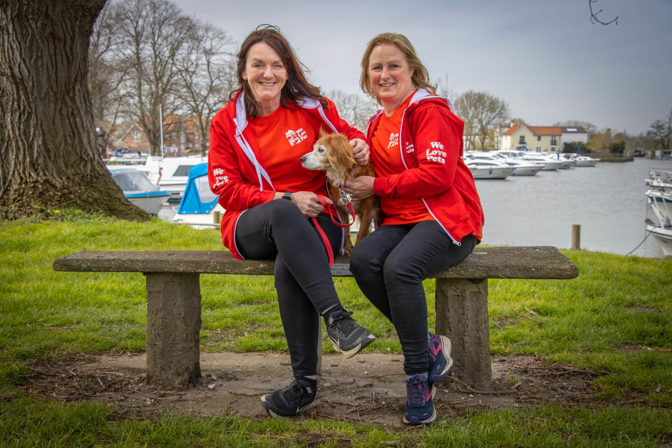 Ruth and Rachael from We Love Pets Woodbridge and Ipswich sitting on a bench holding dog