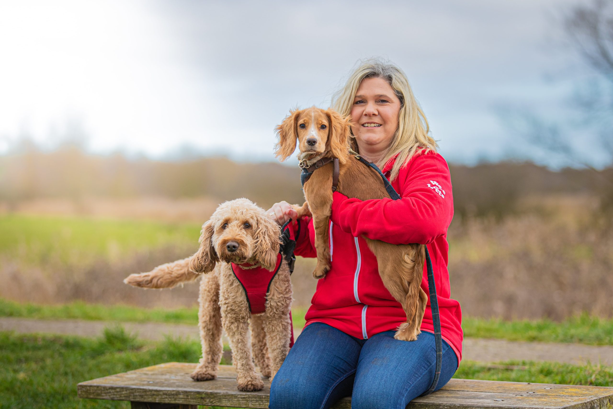 Charlotte from We Love Pets Hertford sitting and holding two dogs